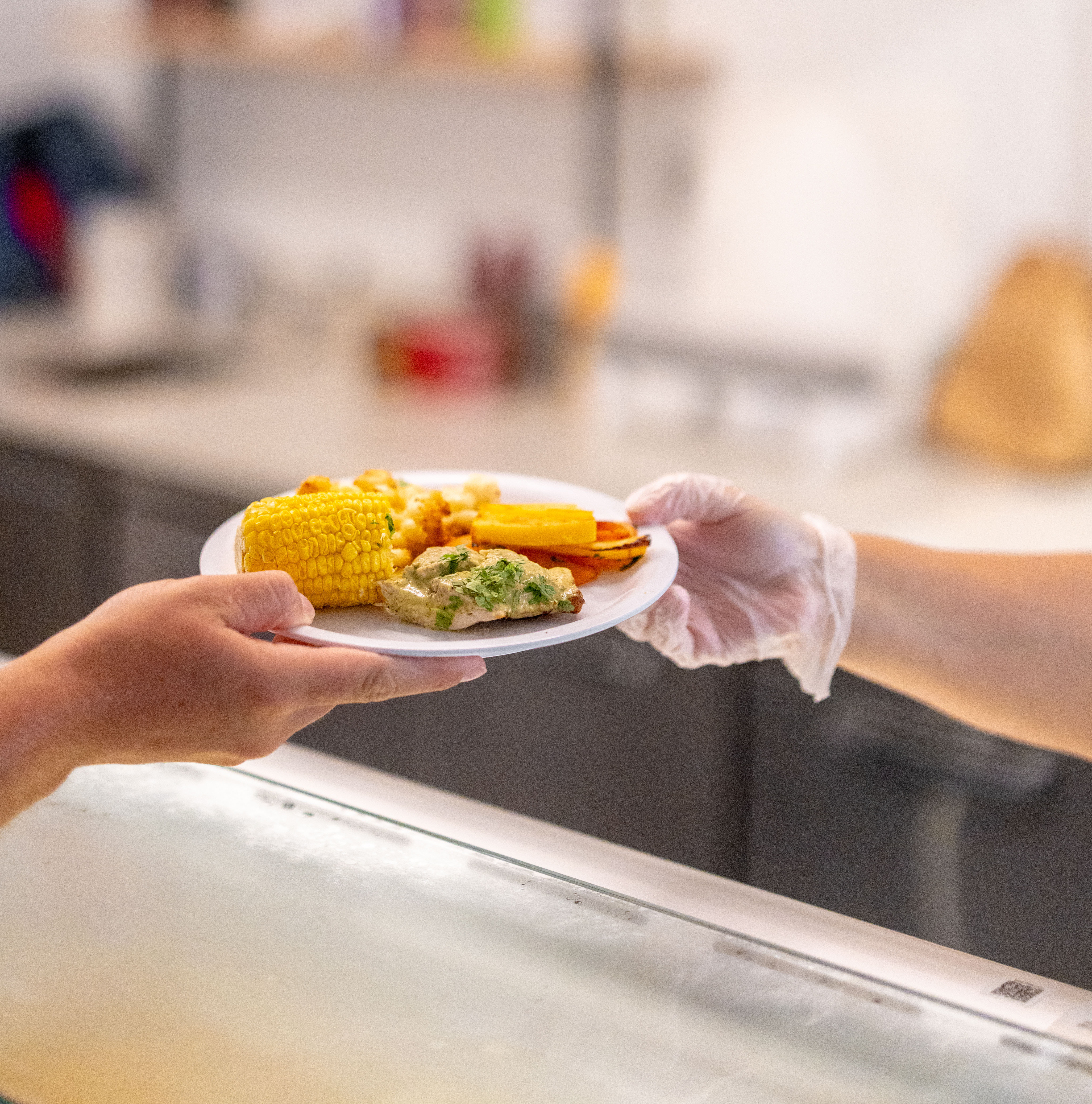 A staff member hands a plate of Halal food to a student at Morrison Dining's dedicated Halal platform.