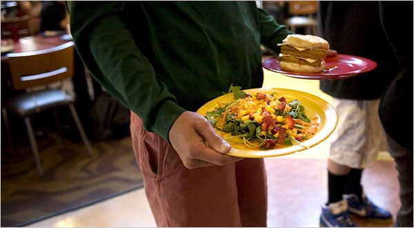 Close-up of hands holding two plates with no tray, in a dining room