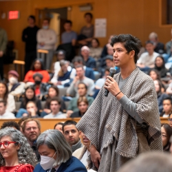 Person speaks into microphone in lecture hall