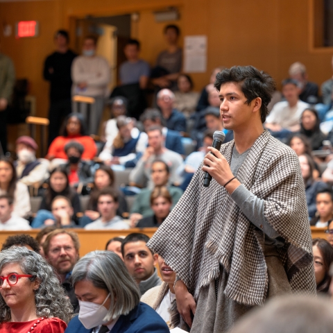 Person speaks into microphone in lecture hall