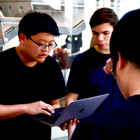 CCRA volunteers work at tables inside Gates Hall during the Bowers Earth Day Repair Fair, with Rubin Dai (left) and other students examining and discussing how to repair a donated MacBook from the Cornell community.
