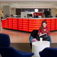 A student sits in a comfortable chair near the help desk.