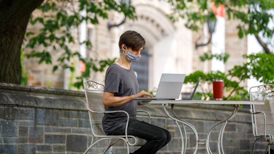 a student wearing a mask while on her computer 